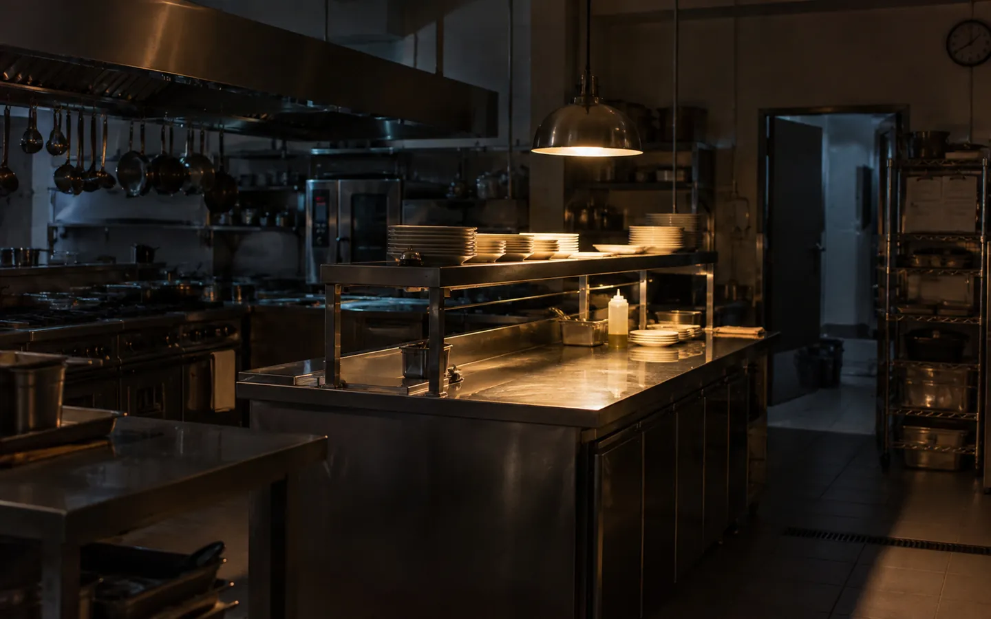 Cucina di ristorante spenta di notte, una sola luce sul pass